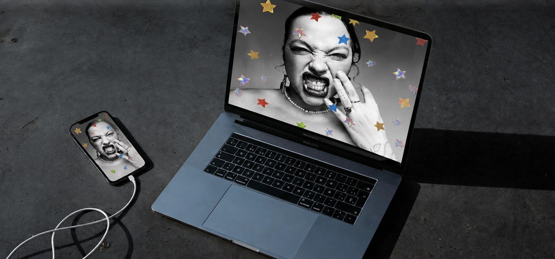 Notebook e celular exibindo retratos em preto e branco com estrelas coloridas